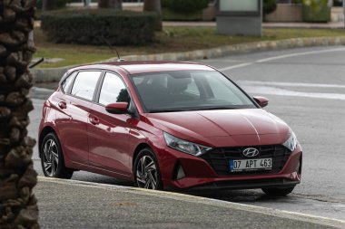 Yan, Türkiye 2 Şubat 2022: Kırmızı Hyundai i20 bir yaz gününde bir parkın arka planına park ediyor 