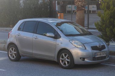 Yan, Türkiye 2 Şubat 2022: Gümüş Toyota Yaris sıcak bir yaz gününde bir binanın, caddenin, dükkanların zeminine park etti 