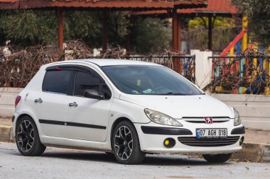 Yan, Türkiye 6 Şubat 2022: Beyaz Peugeot 307, sıcak bir yaz gününde park alanının arka planına park etti 
