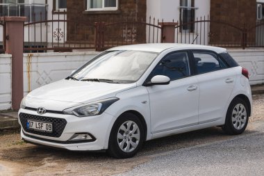 Yan, Türkiye 6 Şubat 2022: Beyaz Hyundai i20 bir yaz günü bir çitin arkasına park ediyor, park 