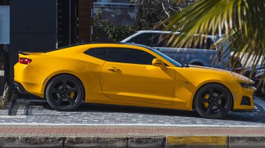 Yan, Türkiye 6 Şubat 2022: Sarı Chevrolet Camaro sıcak bir günde park alanına park etti 