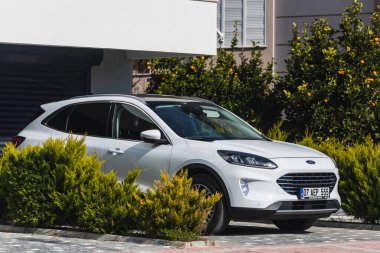 Yan, Türkiye - 22 Ocak 2022: Beyaz Ford Kuga, sıcak bir günde bir evin arka planına, bahçeye park etti.