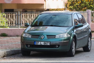 Yan, Türkiye 6 Şubat 2022: Mavi Renault Megane, sıcak bir yaz gününde, bina ve çitlerin arkasına park etti. 