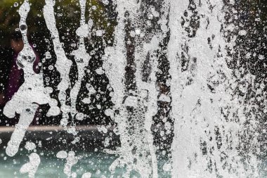 Güneş ışınlarının altında mavi bir zemin üzerinde bir sürü damla ve kabarcık olan su püskürtüleri. Büyük bir plan Büyük bir çeşmenin su dalgalarının dokusu