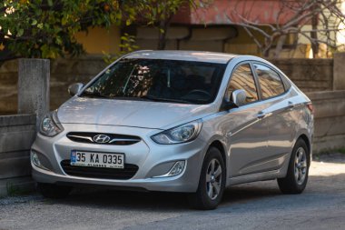 Yana, Türkiye - 13 Şubat 2022: Beyaz Hyundai Solaris sıcak bir günde bir parkın arka planına, çitlere karşı sokağa park edildi