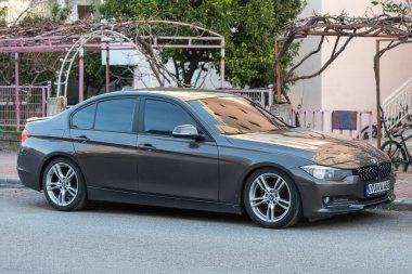 Yan, Türkiye 13 Şubat 2022: Gri BMW 3 serisi sıcak bir sonbahar gününde sokağa park edildi  