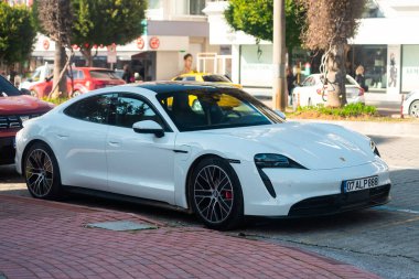 Yan, Türkiye 16 Şubat 2022: Beyaz Porsche Taycan sıcak bir yaz gününde park alanına park etti 