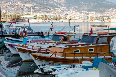 Alanya, Türkiye 16 Şubat 2022: Ahşap kayık tahtaları, beyaz ve kahverengiye boyanmış, deniz suyunun arka planına bağlı halatlarla iskeleye demirlenmiş.. 