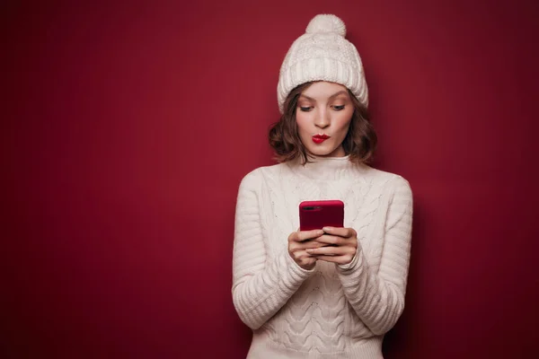 Mujer juguetona en suéter de punto escribiendo en el teléfono Imagen de stock