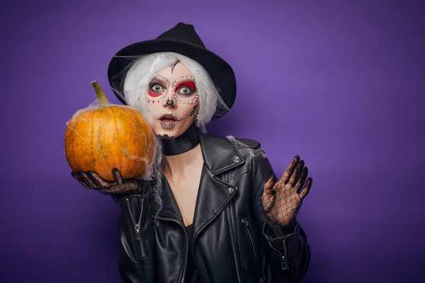Fröhliche junge Frau im Halloween-Kostüm mit Kürbis Stockbild