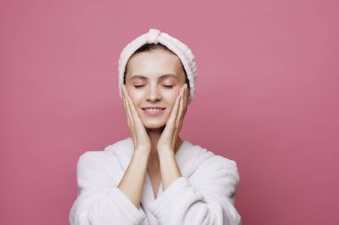 Saçında bantla gülümseyen kız yüzünü temizliyor.