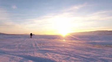 Baykal Gölü. Kız donmuş göl boyunca gün batımına doğru koşuyor. Ogoy Adası 'nda akşam çekimleri.