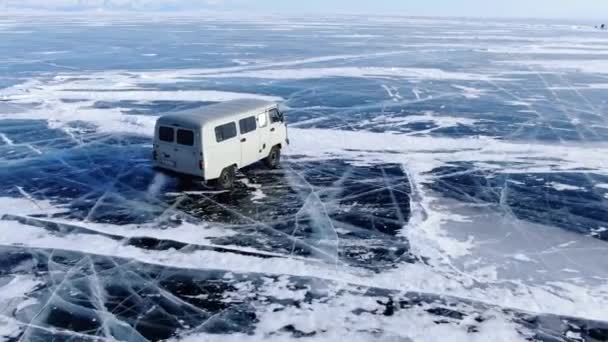 ソ連の白い車Uazは凍結バイカル湖の氷の表面に乗っています サイドビュー 亀裂や雪のドリフトと青い氷 完璧なパノラマビュー — ストック動画