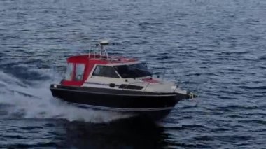 Mavi berrak suların insansız tekne manzarası. Mavi denize doğru giden beyaz bir teknenin üst görüntüsü. Büyük bir sürat teknesi yüksek hızda hareket ediyor. Baykal Gölü boyunca seyahat et..