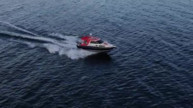 Mavi berrak suların insansız tekne manzarası. Mavi denize doğru giden beyaz bir teknenin üst görüntüsü. Büyük bir sürat teknesi yüksek hızda hareket ediyor. Baykal Gölü boyunca seyahat et..