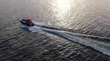 Mavi berrak suların insansız tekne manzarası. Mavi denize doğru giden beyaz bir teknenin üst görüntüsü. Büyük bir sürat teknesi yüksek hızda hareket ediyor. Baykal Gölü boyunca seyahat et..