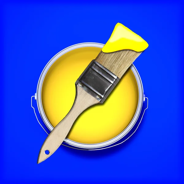 Yellow paint with wet paint brush over a contrasting colored blue background. — Stock Photo, Image