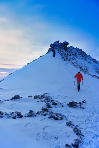 登山家は晴れた冬の日に雪の山の頂上に到達します — ストック写真
