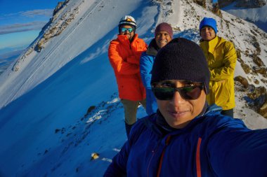 Bir grup yürüyüşçü, turist ya da arkadaş dağın tepesinde fotoğraf çekiyorlar.