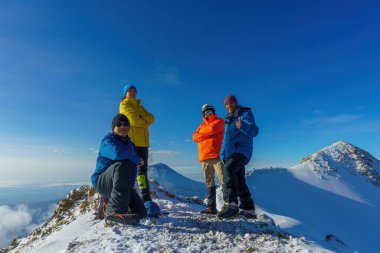 Bir grup yürüyüşçü, turist ya da arkadaş dağın tepesinde fotoğraf çekiyorlar.