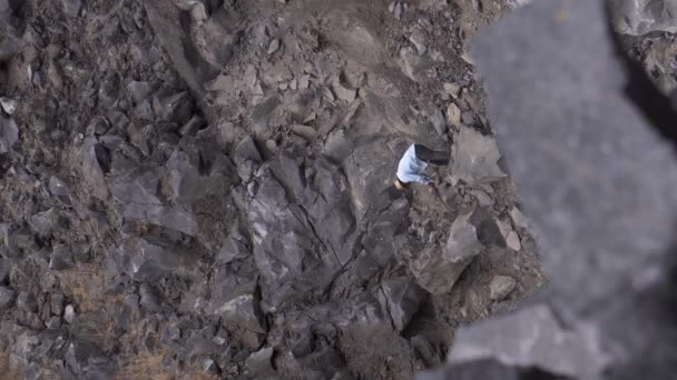 Un hombre local con sombrero trabajando en una mina tratando de remover rocas volcánicas — Vídeo de stock