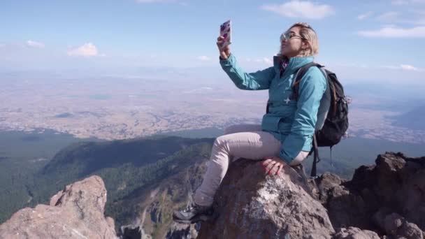 山の中でスマホで写真を撮る青いジャケットの女性 — ストック動画