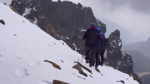 Ομάδα πεζοπόρων ανεβαίνει σε χιονισμένο βουνό κορυφή σε μια φωτεινή χειμωνιάτικη ημέρα — Αρχείο Βίντεο