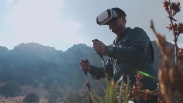 Homem caminha em um campo ao ar livre usando fones de ouvido realidade virtual, ele está se movendo no metaverso. — Vídeo de Stock