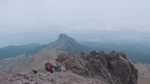 Jovens mochileiros aventureiros caminhando em um topo de montanha acima das nuvens — Vídeo de Stock
