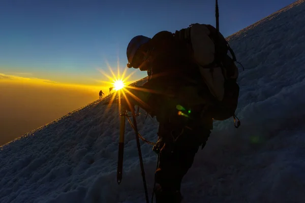 Silueta de montañista al amanecer con hacha de hielo en la mano — Foto de Stock