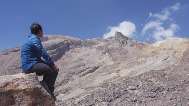 Man zittend op een rots bewondert het landschap van de iztaccihuatl vulkaan — Stockvideo