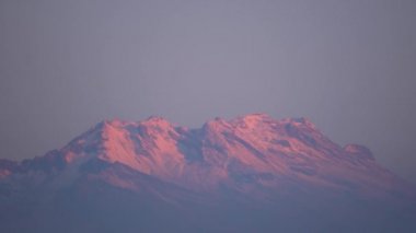 Iztaccihuatl 'ın tepesinde güneş doğarken karla kaplı bir volkan.
