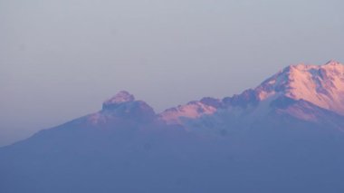 Iztaccihuatl 'ın tepesinde güneş doğarken karla kaplı bir volkan.