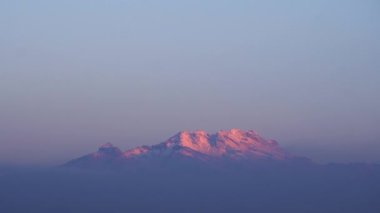 Iztaccihuatl 'ın tepesinde güneş doğarken karla kaplı bir volkan.