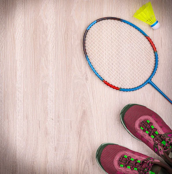 Set di attrezzature sportive con racchette da badminton e scarpe da ginnastica su sfondo in legno — Foto Stock