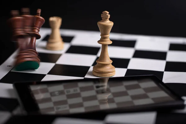 Chess pieces on a chessboard and smartphone. The concept of playing and winning a chess tournament — Stock Photo, Image