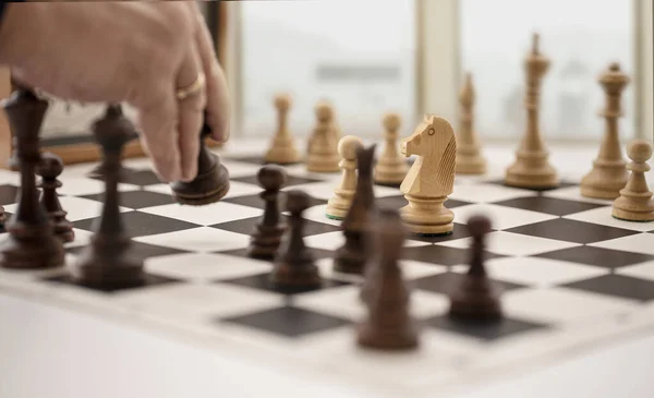 Chess board with clock and figures in front of a blurry window — Stock Photo, Image