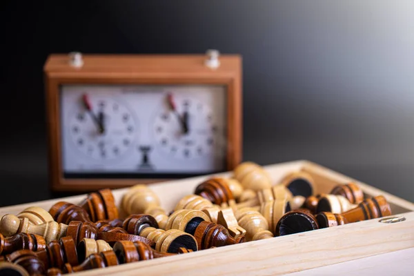 Pièces d'échecs sur un plateau et une horloge d'échecs sur un fond sombre — Photo