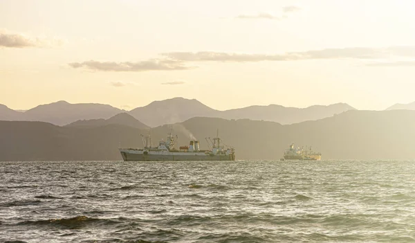 Рибальський корабель у морі на сході сонця на тлі гір — стокове фото