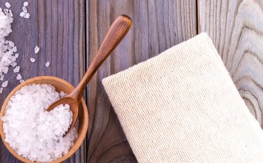 Bardakta deniz tuzu, tahta masada kaşık ve çuval bezi..