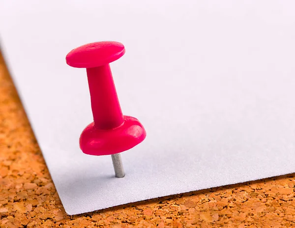 Plastic button with a needle stuck in an iron sheet of white paper on a wooden stopper — Stock Photo, Image