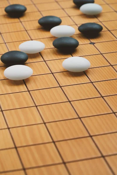 Close up the white stone and black stone of Go board game or Chinese, Japanese classic board game, grid line on wooden board, space for text and design, vertical image.