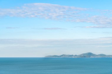 Deniz manzarasının güzel mavi tonu ve dağ, geniş alan gökyüzü bulutlu.