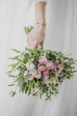 Gelin elinde güzel bir buket gül tutuyor.