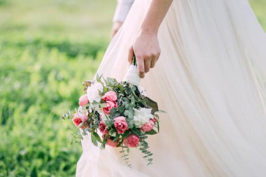 Gelin elinde şakayık güllerinden bir buket tutuyor.