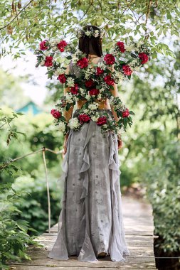 Köprüde nehir perisi suretinde güzel bir genç kadın duruyor. Karanfil kanatları