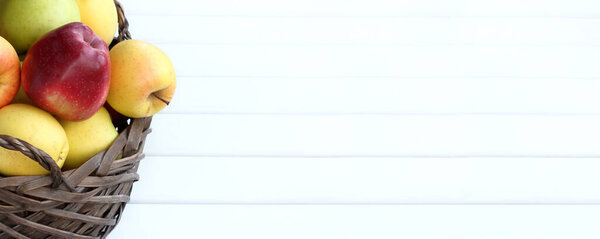 красный, зеленый и желтый яблоки лежат в плетеном контейнере на столе, вид спереди. полная корзина фруктов