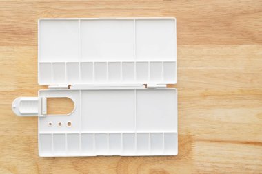 Beyaz suluboya palet. Boş suluboya tepsisi ahşap arka planda izole edilmiş. Beyaz plastik boya paleti.