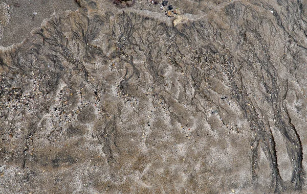 Praia de areia vulcânica molhada com formas e texturas — Fotografia de Stock