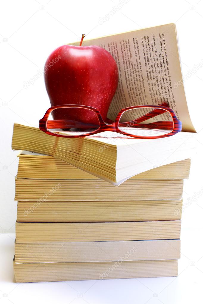 Stack of books with apple and eyeglasses isolated